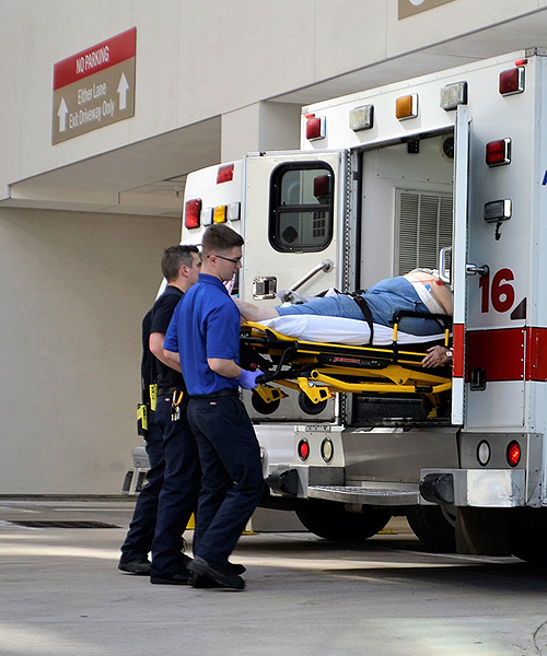 two people loading a stretcher into an ambulance height=
